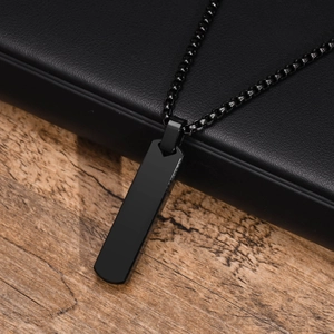 Close-up of sleek black stainless steel rectangular bar pendant on black leather and wood