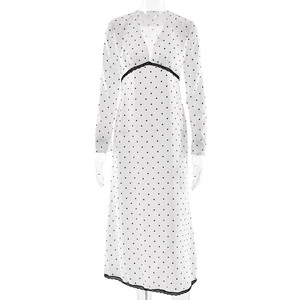 Detailed close-up of V-neckline with black lace trim and polka dot fabric on white dress