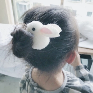 Cute white plush rabbit hair clip worn by a child in soft natural indoor light