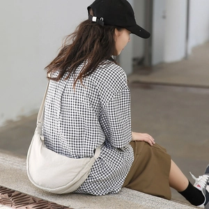 Minimalist beige nylon crescent crossbody bag styled with casual plaid shirt for women