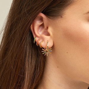 Macro detail of 925 silver needle gold hoop earrings with colorful zircon sunburst charm