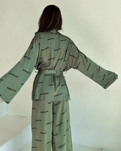 Detail des salbeigrünen Seidenpyjamas mit Logo-Print und Wickelverschluss-Bindung