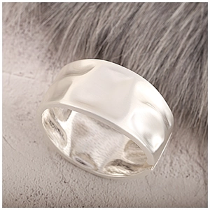 Macro view of wide silver metal cuff bracelet featuring a unique hammered surface texture