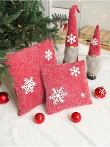 Close-up of red Christmas pillows with white snowflake embroidery on a white rug