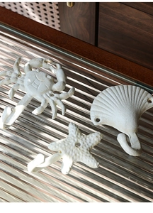 Makro-Detail von Küsten-Wandhaken aus Gusseisen in Form von Krabbe, Muschel und Seestern