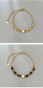 Detailed macro view of tiger eye beads and white pearls on golden stainless steel bracelets