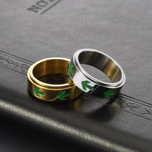 Close-up of gold and silver rotating fidget rings with green arrows on leather surface