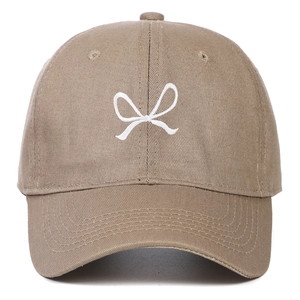 Detail of white bow embroidery on a khaki soft cotton baseball cap with ventilation eyelets