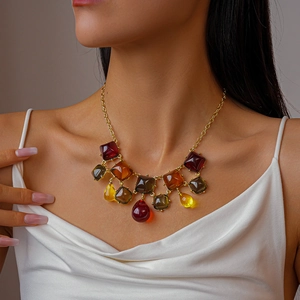 Détail macro de pendentifs géométriques en résine sur un collier doré en alliage