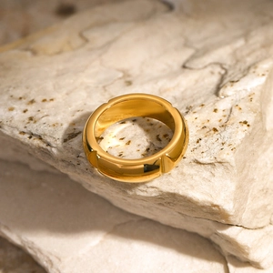 Detail view of segmented 18k gold stainless steel ring on a natural beige stone texture