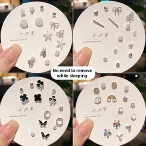Close-up of assorted petite stud earrings with pearl, star, and bow designs on a display card