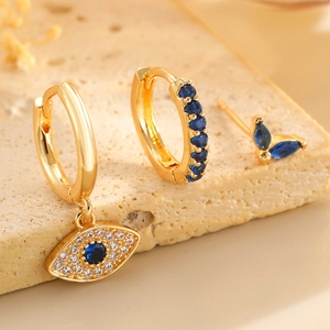 Macro view of gold devil eye earrings set with blue and white zircon stone inlay