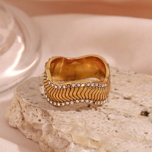 Macro shot of 18K gold plated wide band ring with wavy texture and double row of zircons