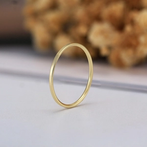Macro di un anello sottile minimalista in argento S925 dorato su uno sfondo dai toni caldi