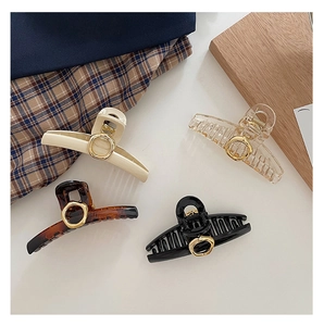 Detailed set of four elegant hair clips in beige, amber, black, and clear with gold circles