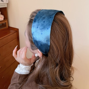 Detail of dark blue velvet headband with polka dots worn on a model with pearl earring