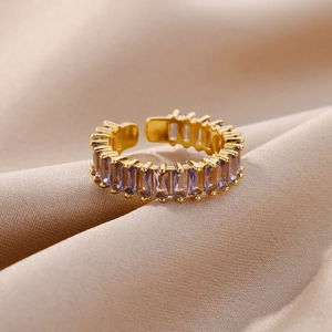 Macro view of adjustable gold ring with emerald cut purple zircons on silk background