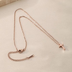 Detailed macro view of a rose gold stainless steel cross pendant with S.STEEL engraved tag