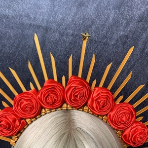Detail of halo crown with red satin roses and golden spikes on a grey background