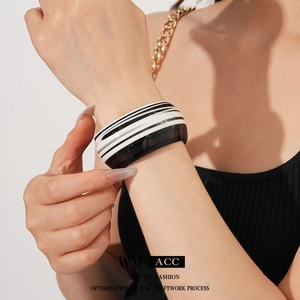 Minimalist wide striped acetate open bangle in black and white worn on a model wrist
