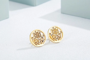 Macro shot of gold-plated circular Hamsa hand stud earrings with a central crystal accent