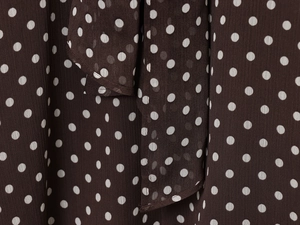 Close-up of brown chiffon fabric featuring white polka dots and delicate ruffle details