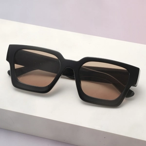 Detail view of thick black square sunglasses with light brown lenses on a display stand
