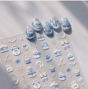 Vista macro di adesivi 3D natalizi per unghie con motivi di pupazzo di neve e fiocchi di neve