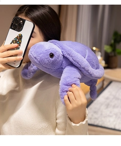 Soft purple plush sea turtle toy held by a model in a cozy lifestyle home setting