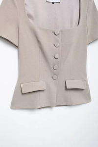 Detail view of khaki short-sleeve blazer featuring a square neck and cloth-covered buttons
