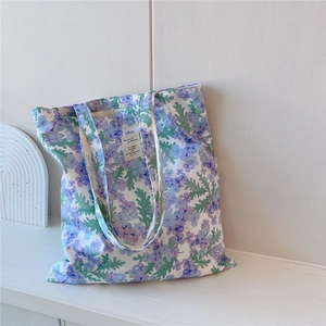 Détail d'un sac cabas en coton fleuri avec imprimé violet et étiquette tissée