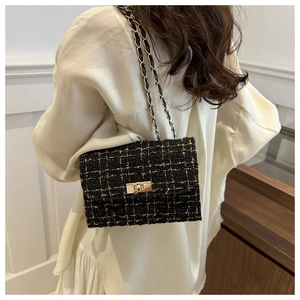 Detailed close-up of a black tweed shoulder bag with gold chain strap worn by a model
