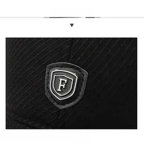 Detail of black twill baseball cap showing shield logo and metal letter F on fabric