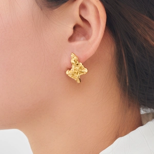 Boucles d'oreilles fleurs triangulaires en acier doré texture lave sur mannequin
