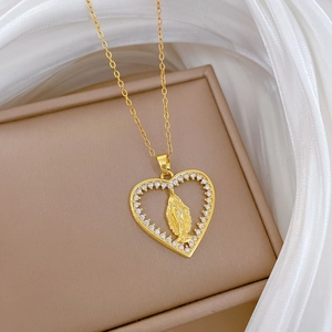 Dettaglio macro di una collana in oro a cuore con zirconi e rilievo della Vergine Maria