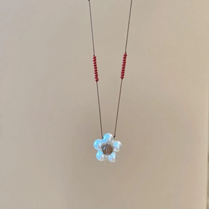 Detail of flower pendant necklace with white pearl beads and dark brown cord