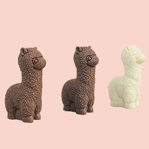Three cute alpaca shaped resin figures in brown and white colors on pink background
