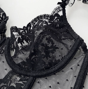 Detailed macro view of black floral embroidery and polka dot mesh lace on the bra cup
