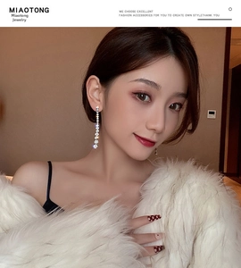 Close-up of long silver fringe earrings with sparkling white crystals on model