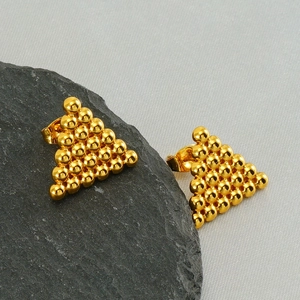 Boucles d'oreilles triangles dorées composées de perles sur une roche noire