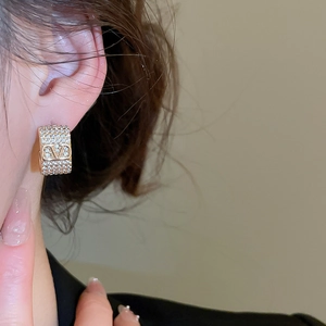 Detail of a gold-plated earring with sparkling crystals on a model's earlobe