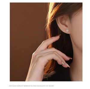 Macro detail of hollow rose flower stud earring in silver on a model's ear lobe
