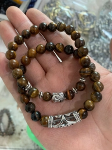 Detail of luxury men's beaded bracelets featuring brown tiger eye stones and silver Buddha head