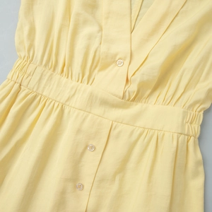 Detail of V-neckline and buttoned waist on light yellow long sleeve ruffle dress