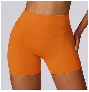 Detail of high-waisted orange yoga shorts showing seamless stitching and elastic fabric