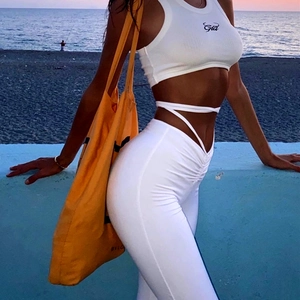 Detail of white modal crop top and lace-up yoga pants with side-view on the beach