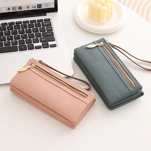 Detail of pink and blue lychee leather wallets with gold leaf zippers and wrist straps