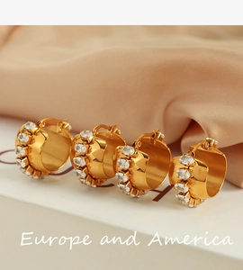 Detailed view of gold C-shaped earrings with inlaid oval cubic zirconia on satin background