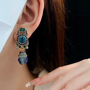 Close-up of vintage gold clip earrings with blue and green crystals on a model