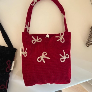 Détail du sac en velours côtelé rouge avec broderie nœud crème et fermoir magnétique